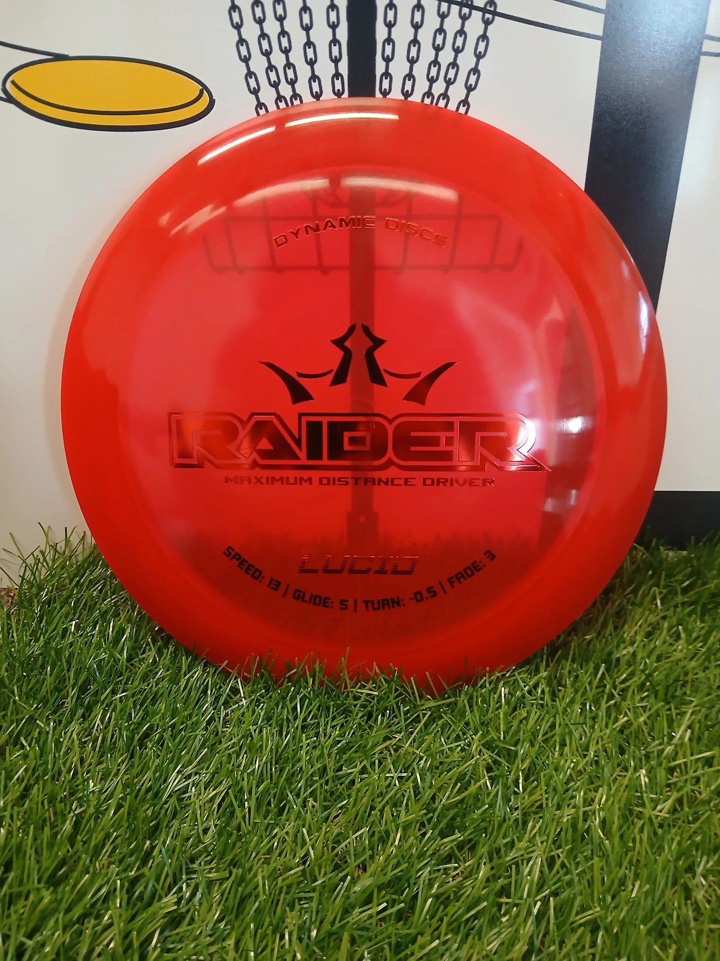 Red Dynamic Discs Raider maximum distance driver disc on grass, Lucid plastic