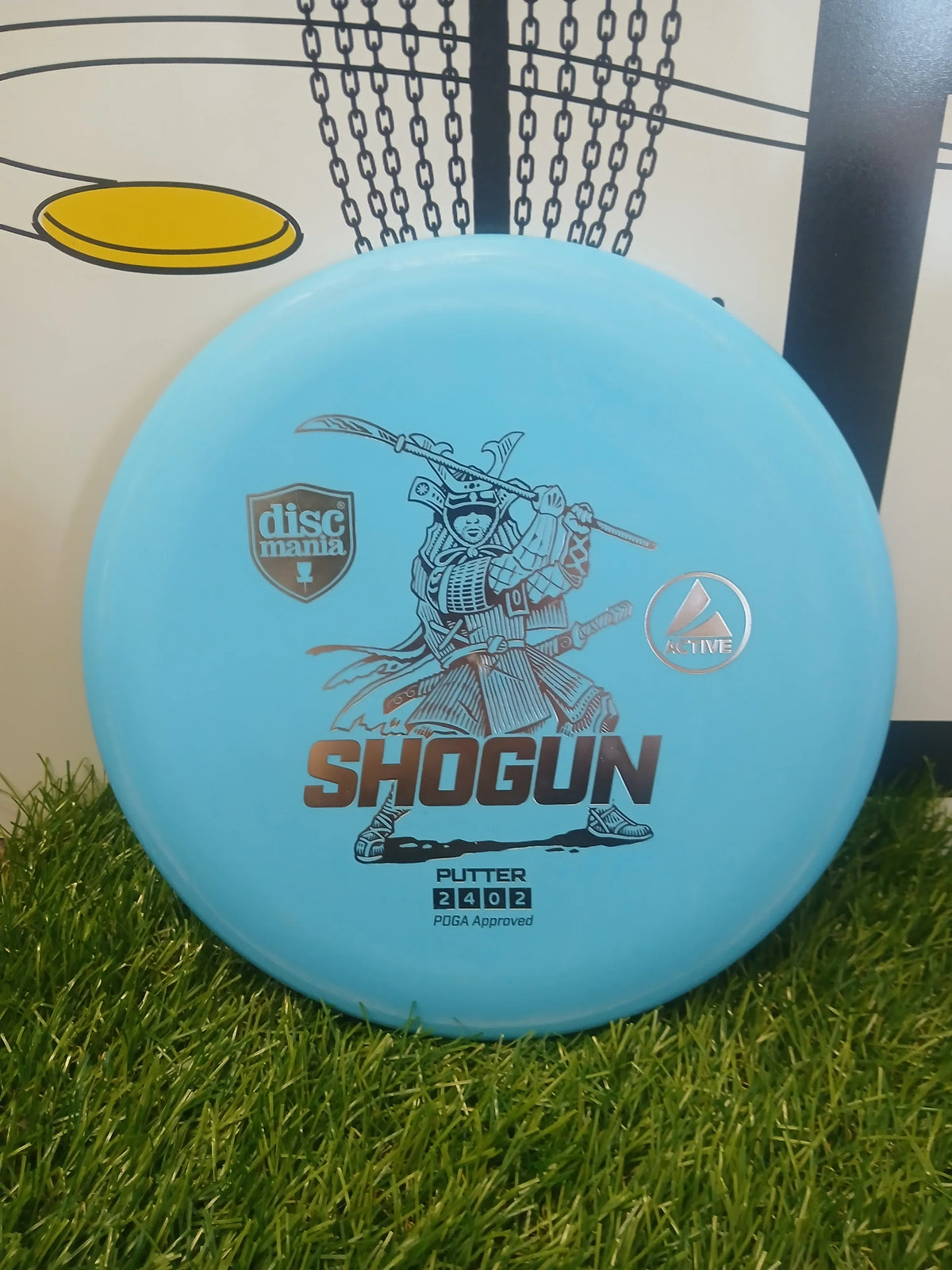 Discmania Shogun Active putter disc golf disc on grass, PDGA approved for disc golf courses
