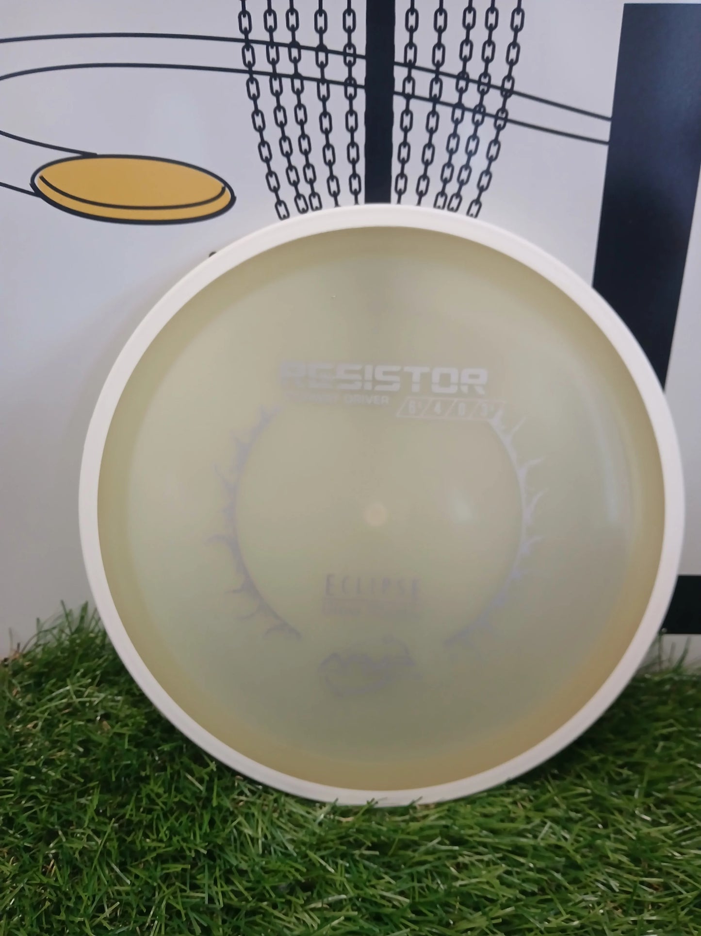 Resistor fairway driver disc golf disc on grass with chain basket background