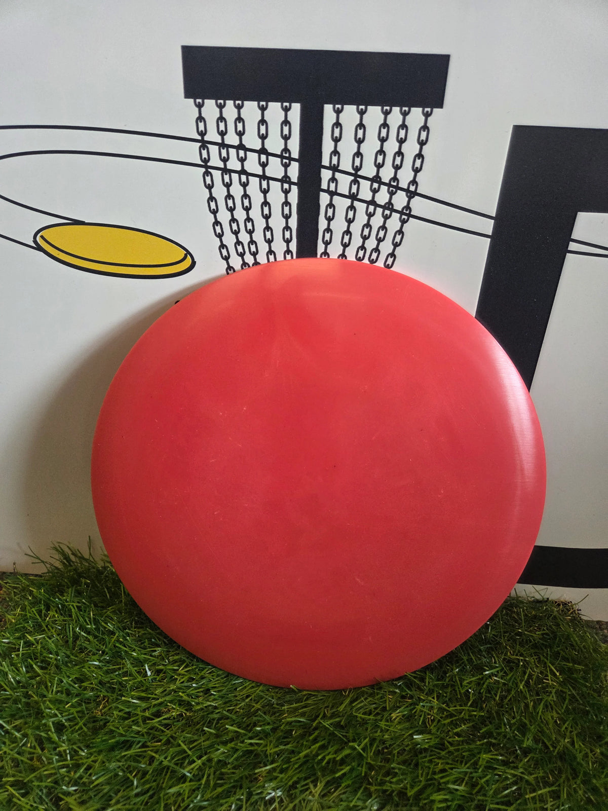 Red disc golf disc on grass with basket graphic background