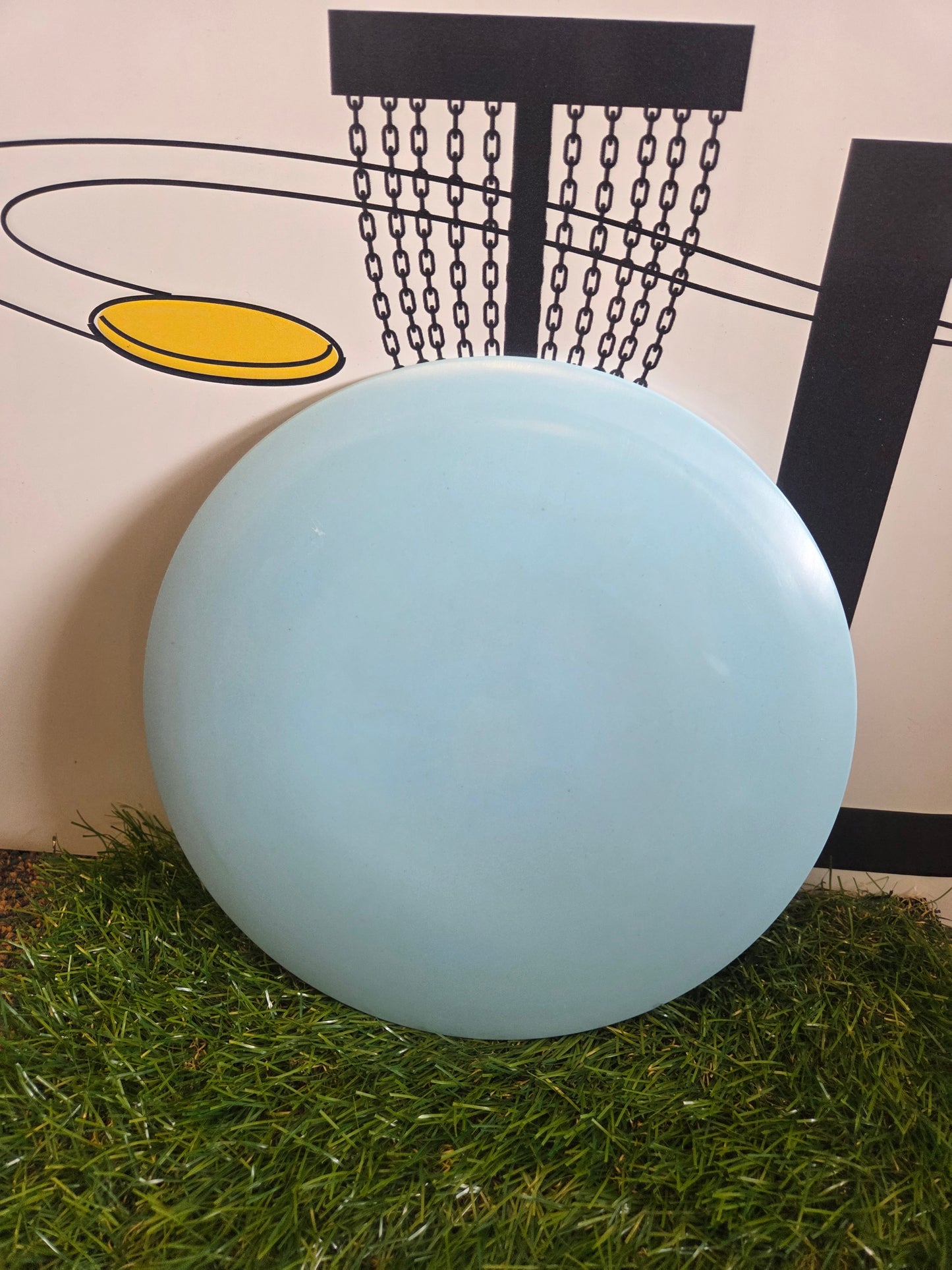 Light blue disc golf disc on grass with basket graphic background