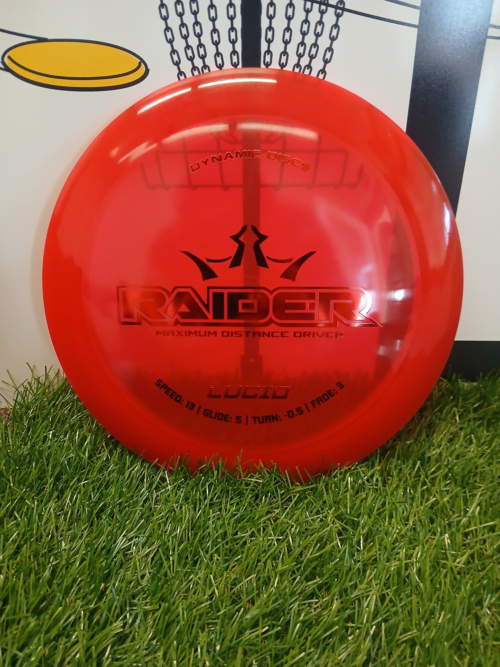 Red Dynamic Discs Raider maximum distance driver disc on grass, Lucid plastic