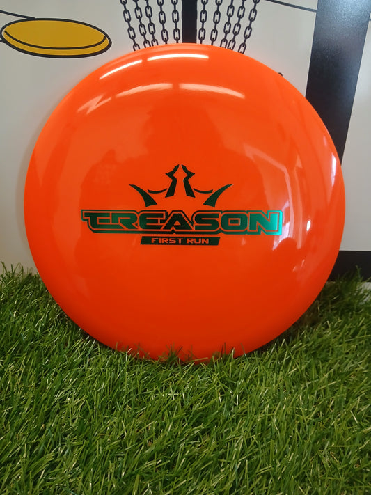 Bright orange Treason First Run disc golf disc on artificial grass, ideal for disc golf enthusiasts and players.