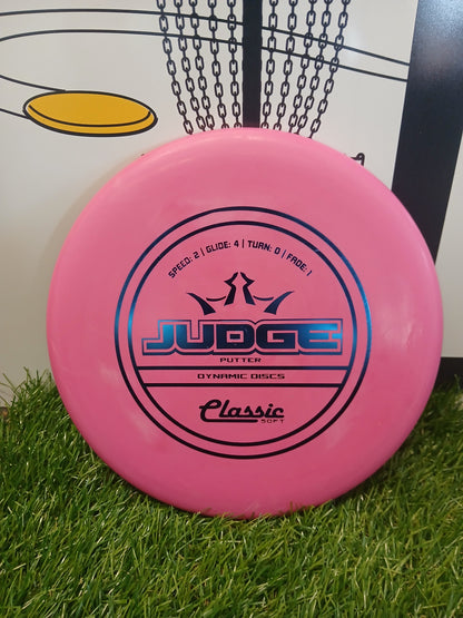 Pink Dynamic Discs Judge putter disc on grass, ideal for disc golf beginners and pros.