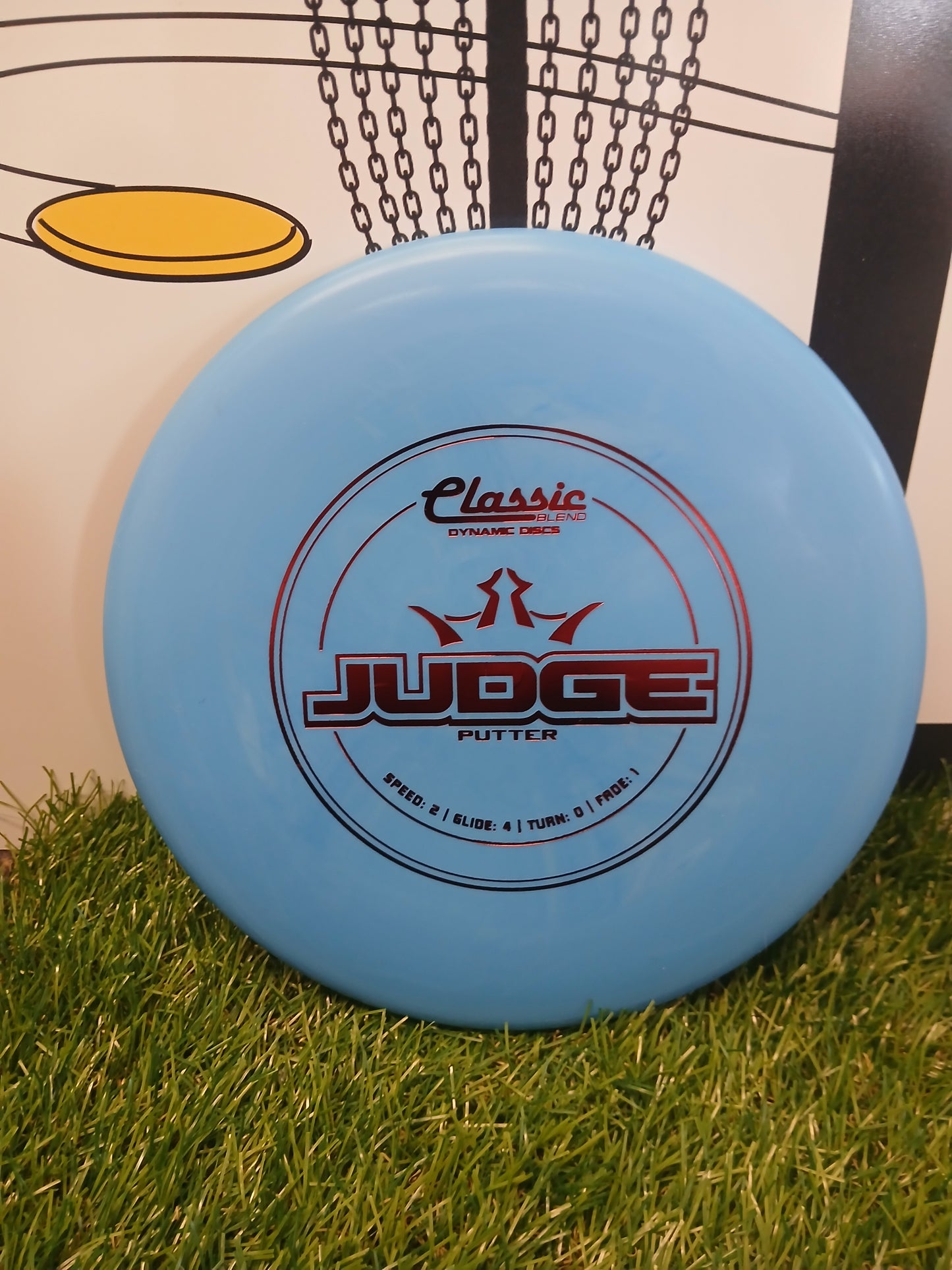 Light blue Dynamic Discs Judge putter disc on grass, ideal for disc golf beginners and pros.