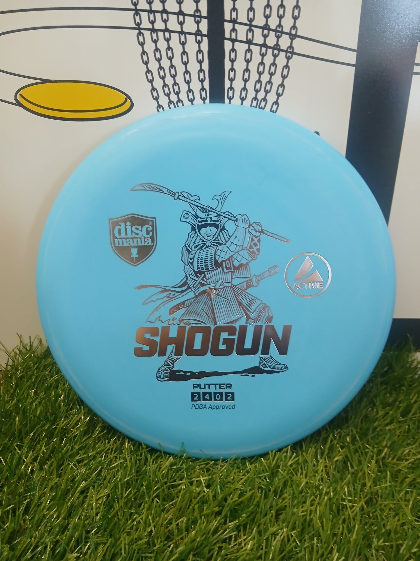 Discmania Shogun Active putter disc golf disc on grass, PDGA approved for disc golf courses