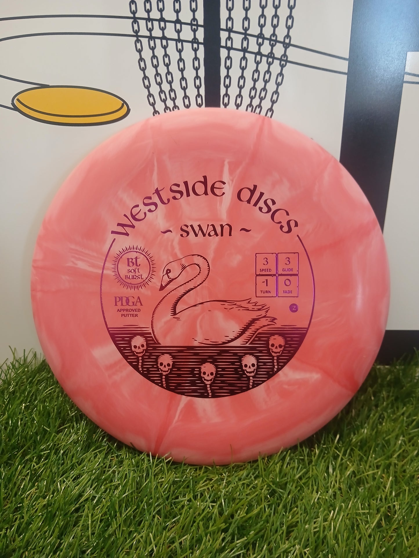 Pink Westside Discs Swan putter on grass, PDGA approved with swan and skull design