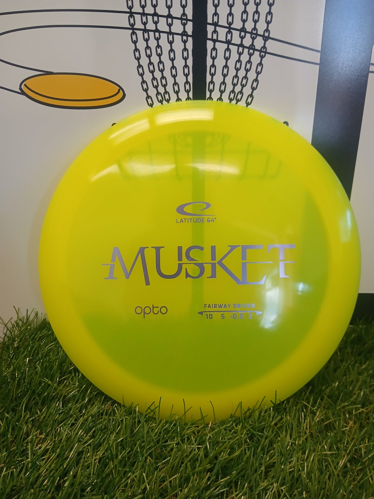 Bright yellow Latitude 64 Musket Opto fairway driver disc golf disc on grass
