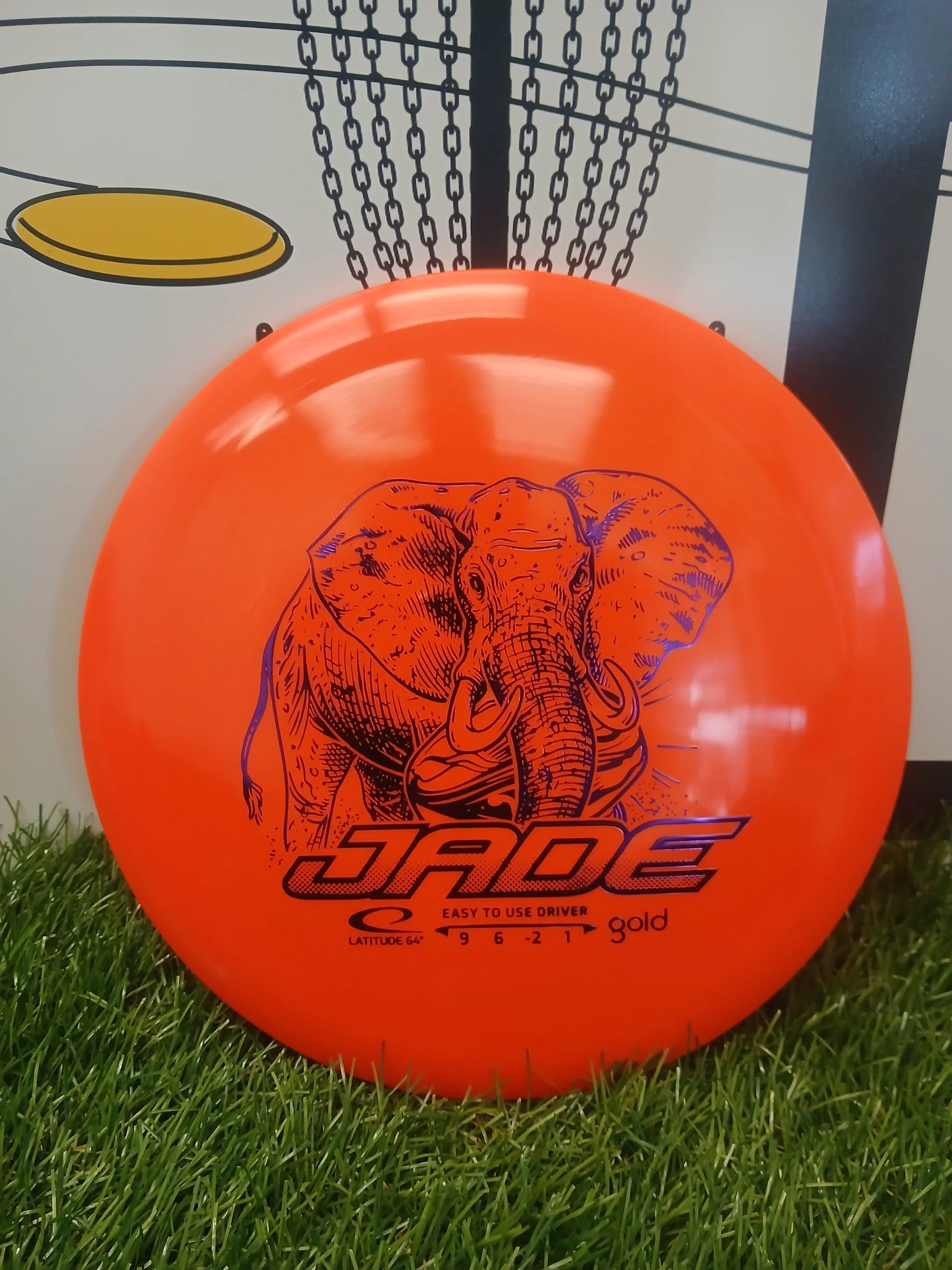 Bright orange disc golf driver with elephant design, labeled 'Jade' for easy use on grassy terrain.