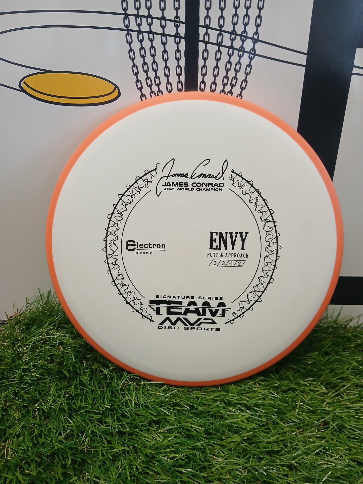 James Conrad 2021 World Champion Envy putter disc, Electron plastic, Team MVP Disc Sports, on grass near basket