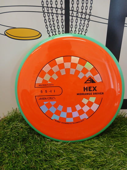 Orange HEX midrange driver disc golf disc with checkered design on grass
