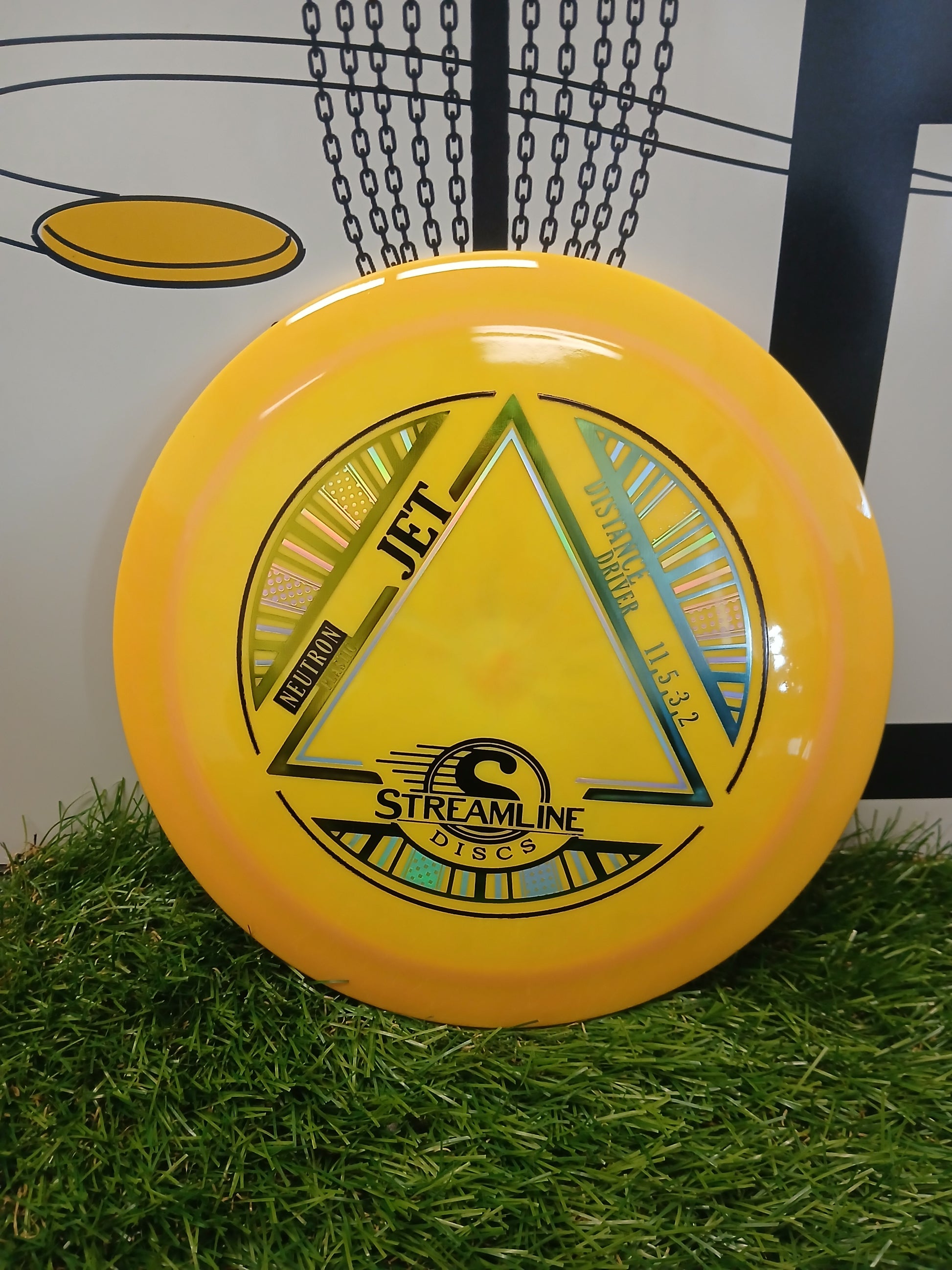 Yellow Streamline Discs Jet Neutron distance driver on artificial grass with chain-link backdrop