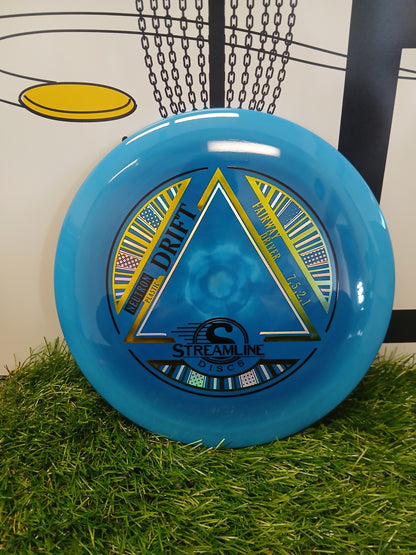 Blue Streamline Discs Drift fairway driver on artificial grass with chain basket background