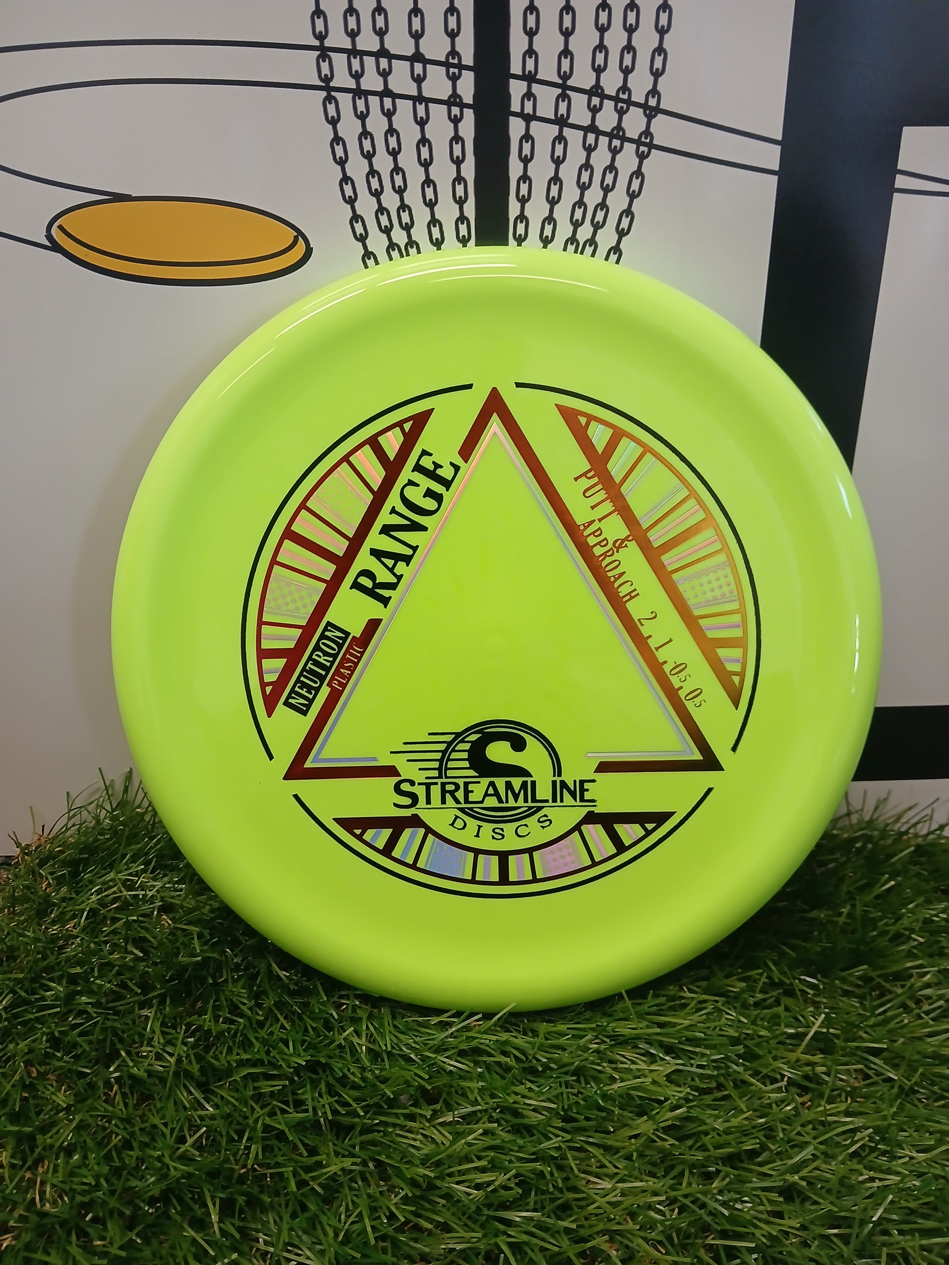Bright green Streamline Discs Neutron Range putter & approach disc on grass, ideal for disc golf.