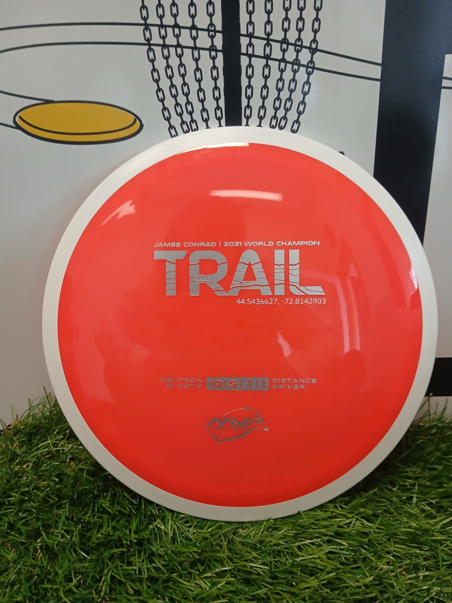 Red MVP Disc Sports Trail distance driver disc on grass, James Conrad 2021 World Champion edition