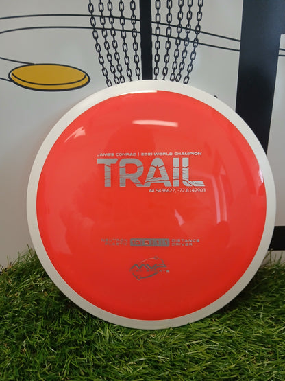 Red MVP Disc Sports Trail distance driver disc on grass, James Conrad 2021 World Champion edition