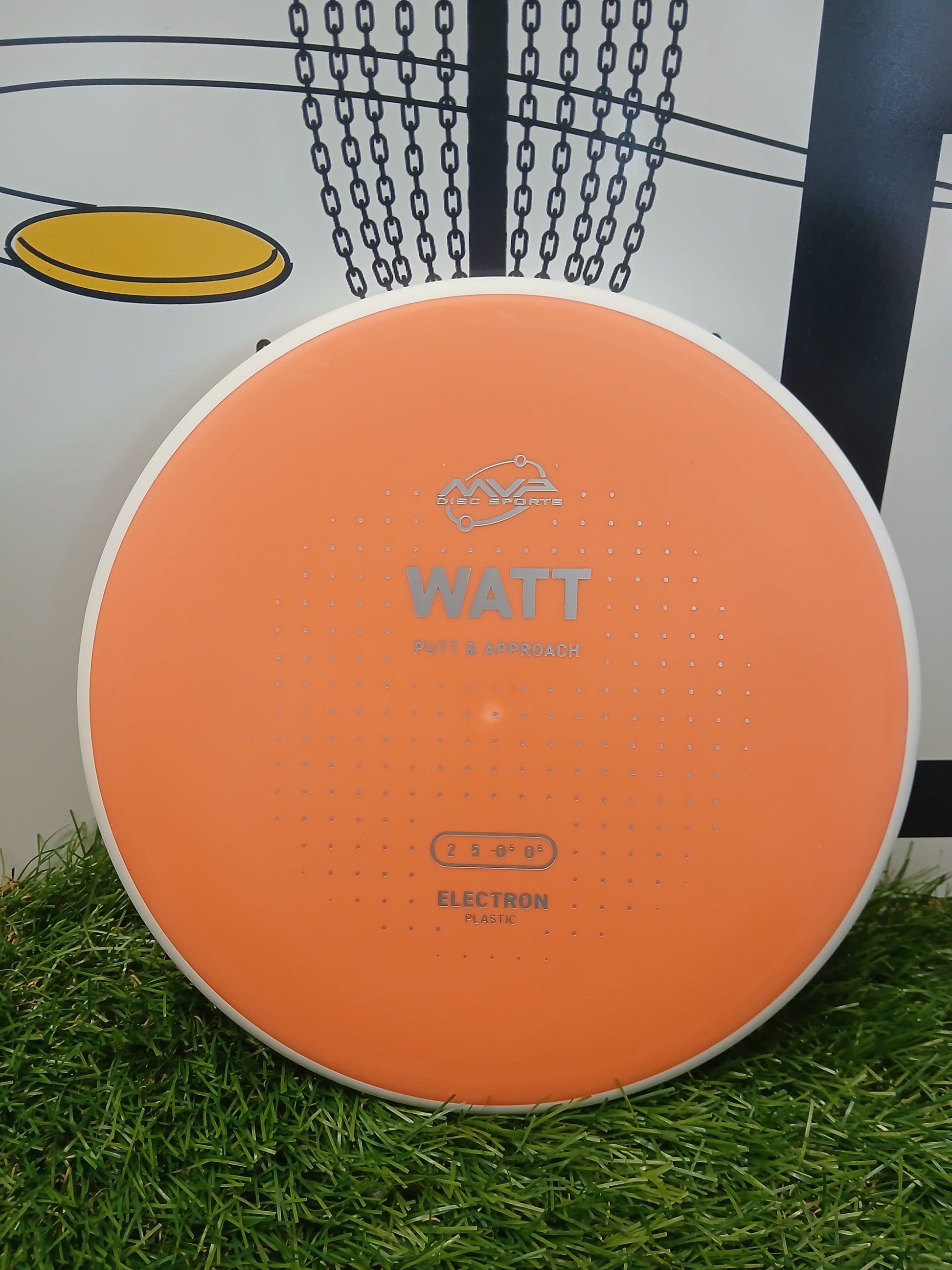 Orange MVP Disc Sports Watt putter disc on grass, ideal for disc golf putt & approach shots.