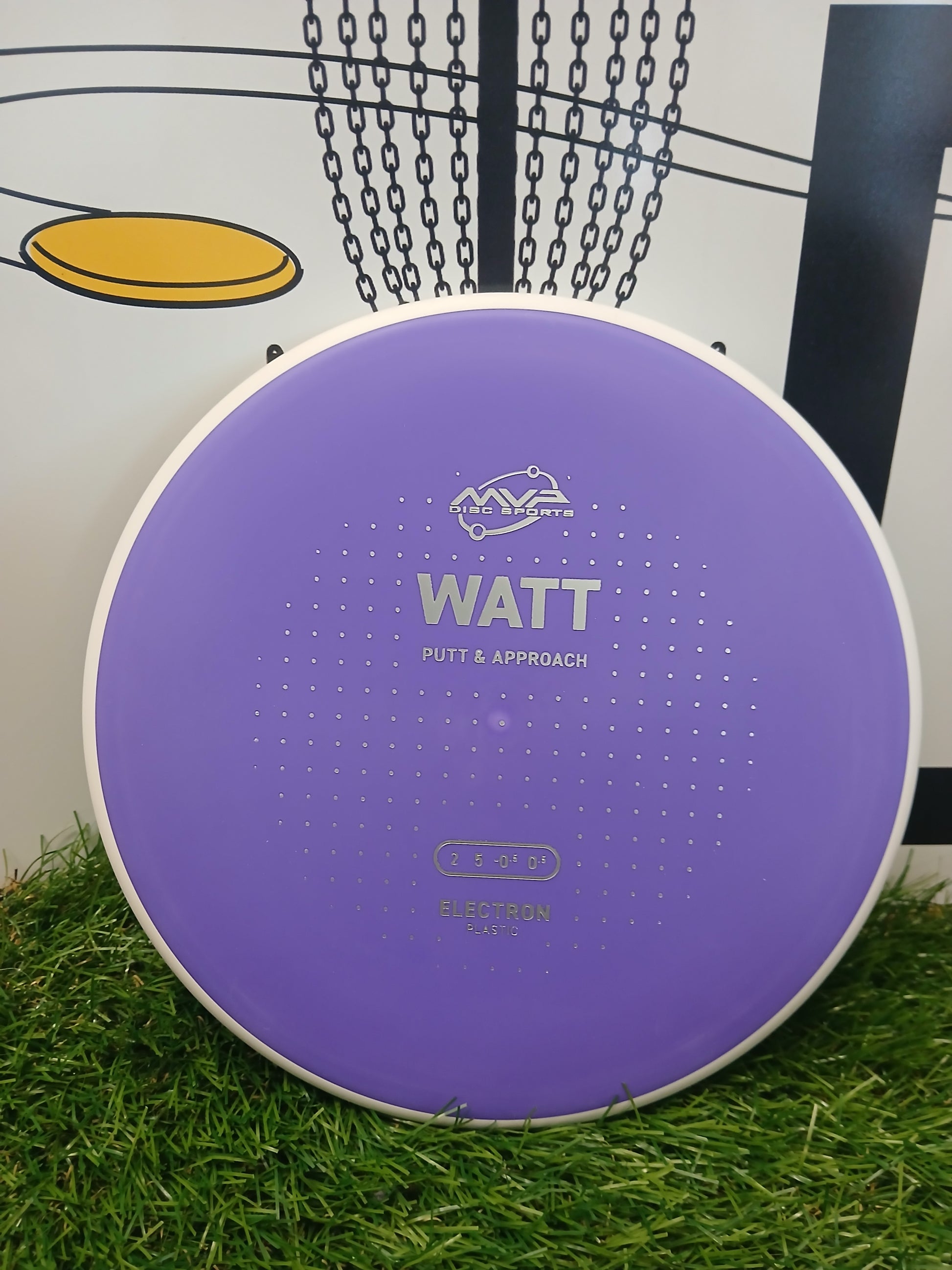 Purple MVP Disc Sports Watt putter disc for disc golf, Electron plastic, on grass near basket