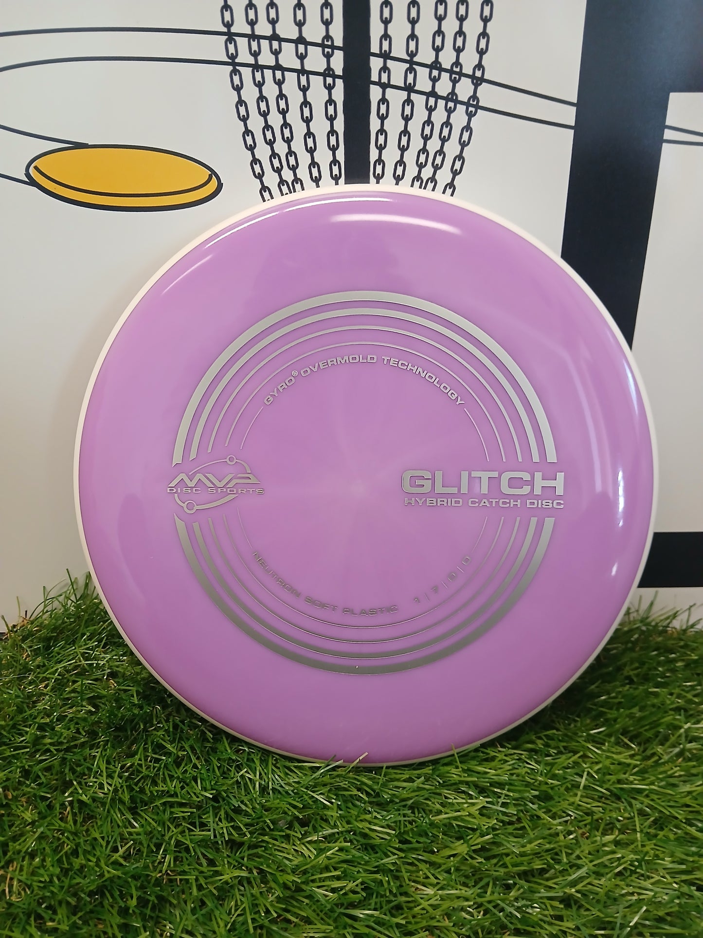 Purple MVP Glitch hybrid catch disc on grass, featuring Gyro Overmold tech for disc golf practice