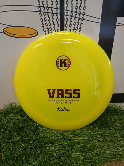 Bright yellow Kastaplast Vass distance driver disc golf disc on artificial grass, ideal for long throws.