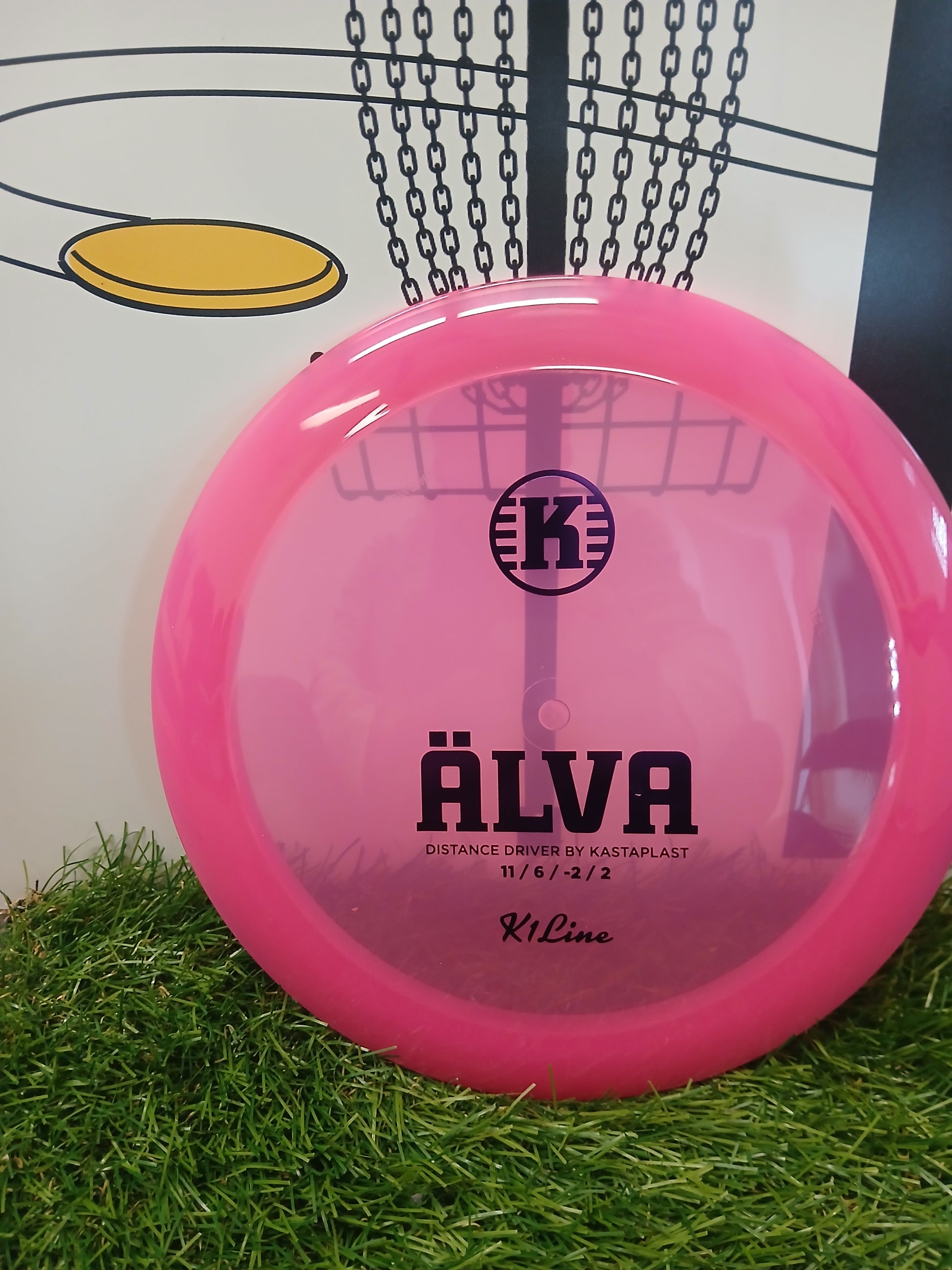 Pink Kastaplast Älva distance driver disc golf disc on grass, K1 Line, 11/6/-2/2 flight ratings