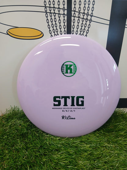 Purple Kastaplast Stig midrange disc golf driver on grass, K1 Line, with chain basket graphic